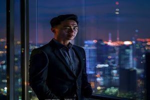 陈磊，磁力天堂创始人兼首席执行官，身着深色商务休闲装，站在公司办公室落地窗前，神情自信从容，背景是城市夜景与闪烁的霓虹灯光